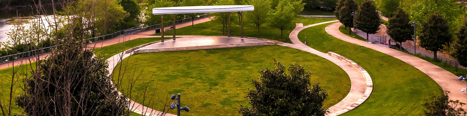 A city skyline with a prominent bridge and a park with a curved pathway.
