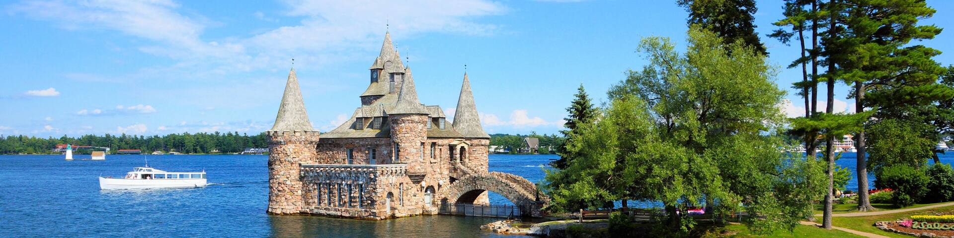 A historic stone castle with three towers on a lakeside.