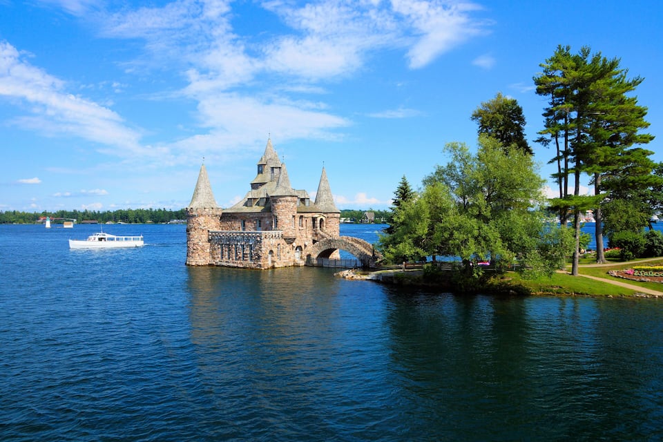 Un castillo de piedra histórico con tres torres a orillas de un lago.