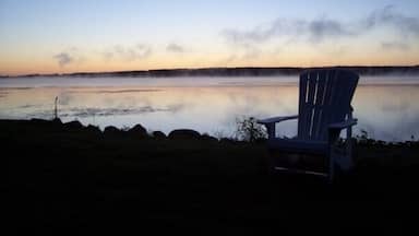 Uma cadeira perto de um lago tranquilo ao entardecer.