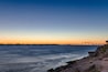 A sunset over a body of water with a bridge in the background.