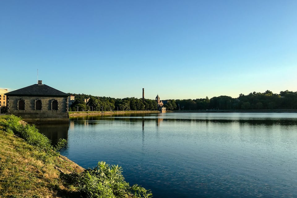 Un llac tranquil amb un edifici de pedra i una església a la riba contrària.
