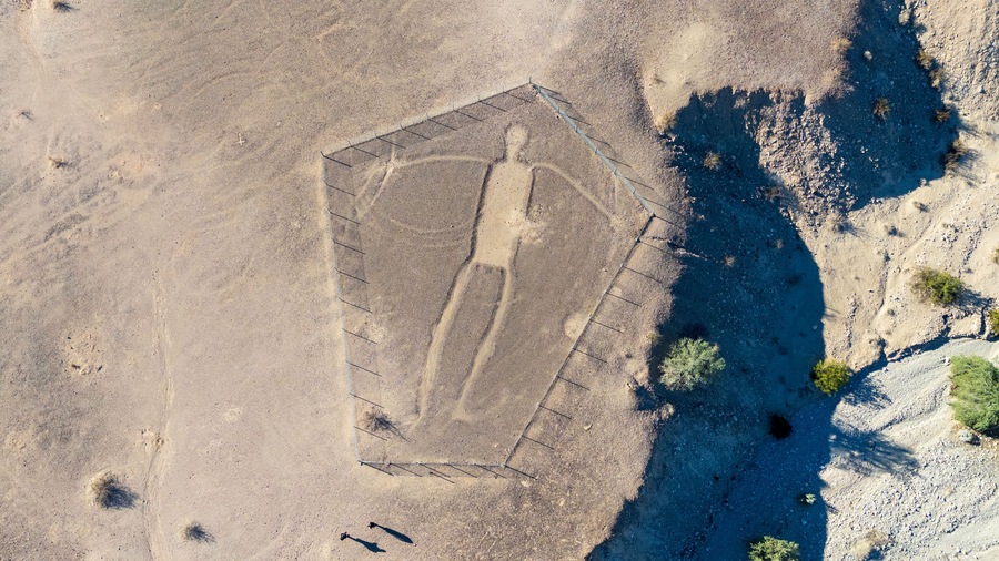 Blythe Intaglios Aerial View – Main Human Geoglyph, California Desert. Ancient desert figure near Blythe with visible erosion channel approaching fence, showing natural wear over time.