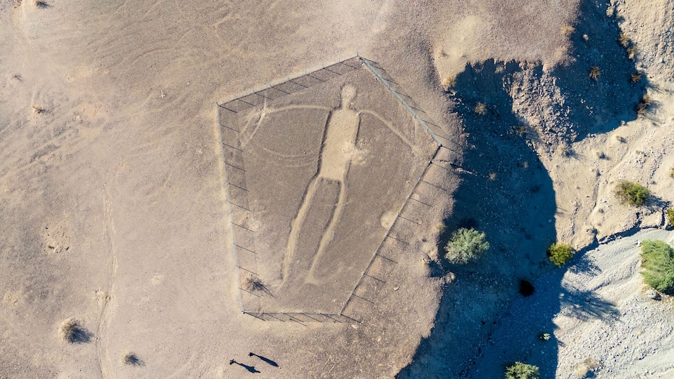 An aerial view of a fenced area with a rectangular shape, surrounded by desert terrain and sparse vegetation.