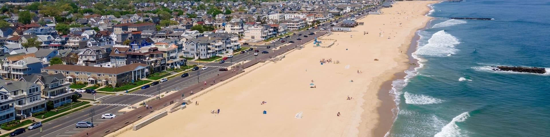 Drone shot of the Belmar Beach and coastal road and buildings on a sunny day in Belmar, New Jersey