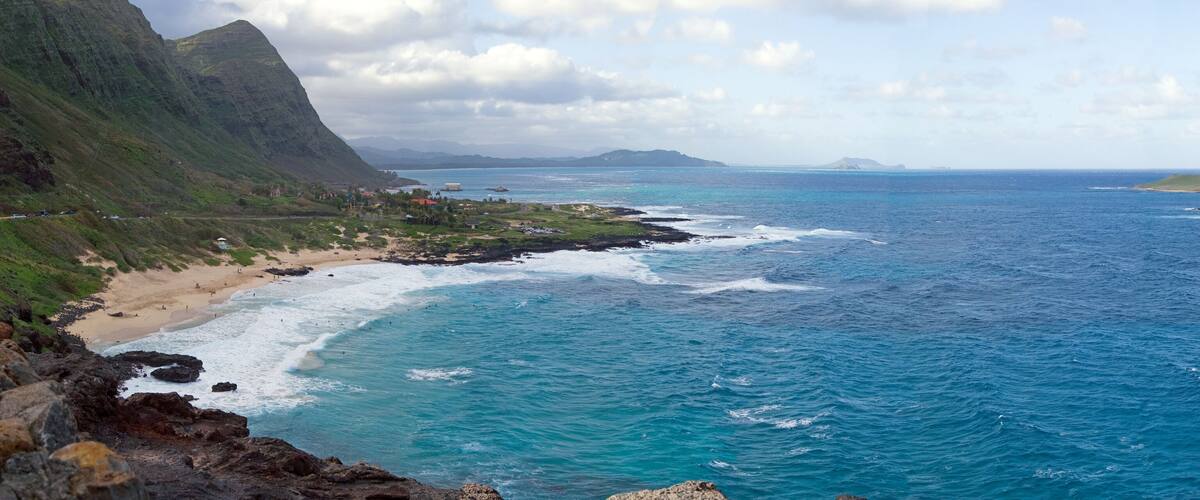 A coastal landscape with a beach, rocky coastline, and a prominent hill.