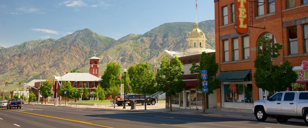 A street with a hotel, mountains, and a clock tower.