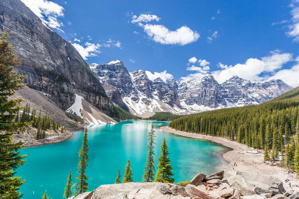 A turquoise lake surrounded by mountains and dense forests.