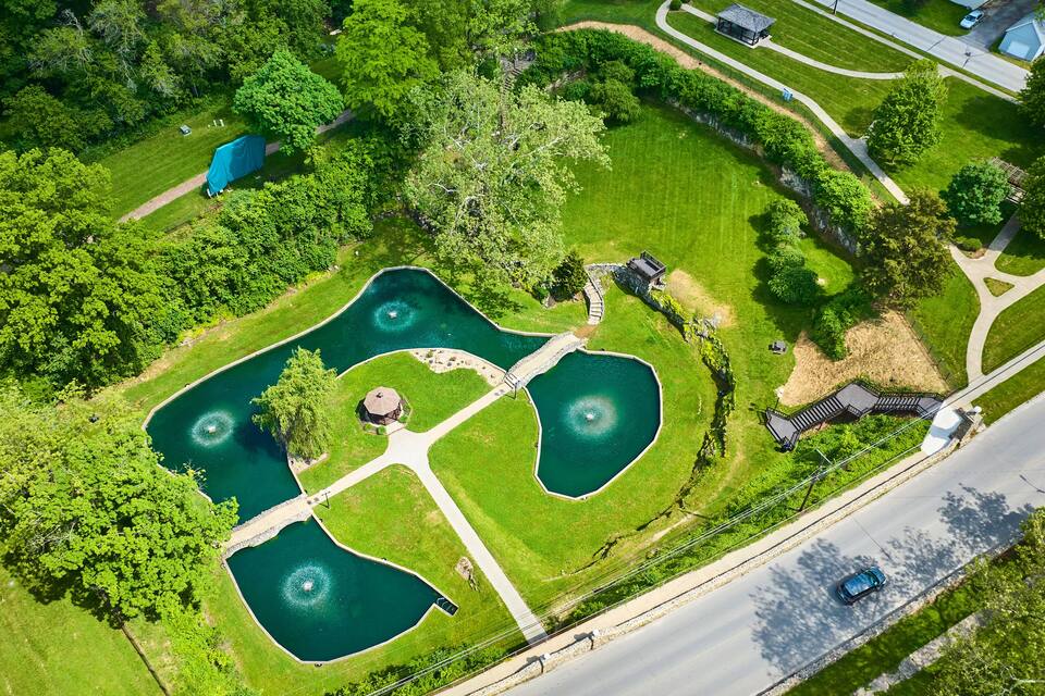 An aerial view of a park with multiple ponds, walking paths, and surrounding greenery.