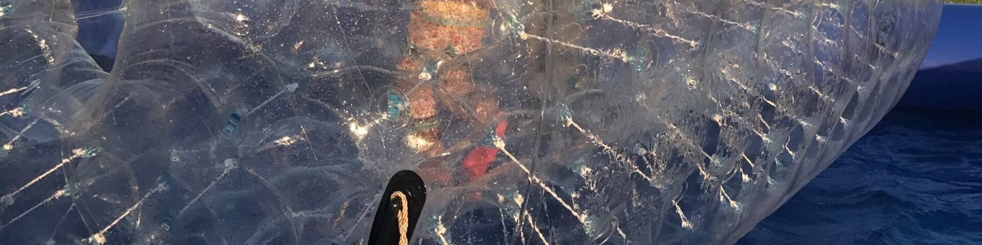 A transparent, spherical structure with a rope tether, reflecting its surroundings.