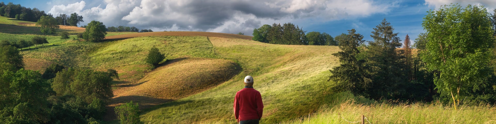 A hike in an amazing landscape with rolling hills. Hiker walking on a scenic path through meadows.