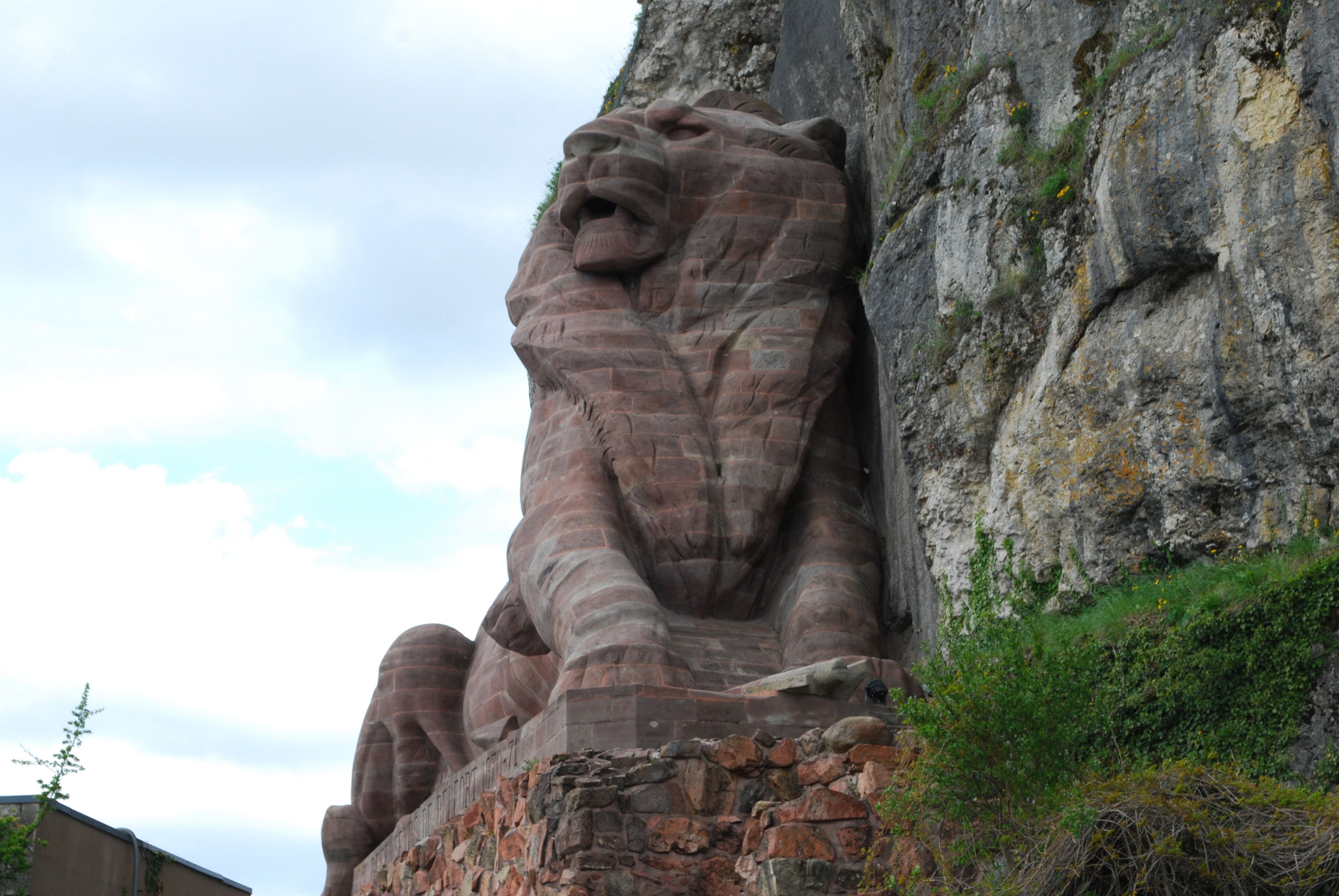 A large stone lion sculpture on a cliff.