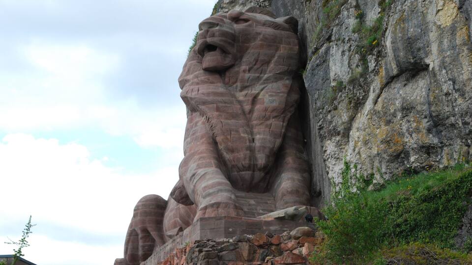 A large stone lion sculpture on a cliff.