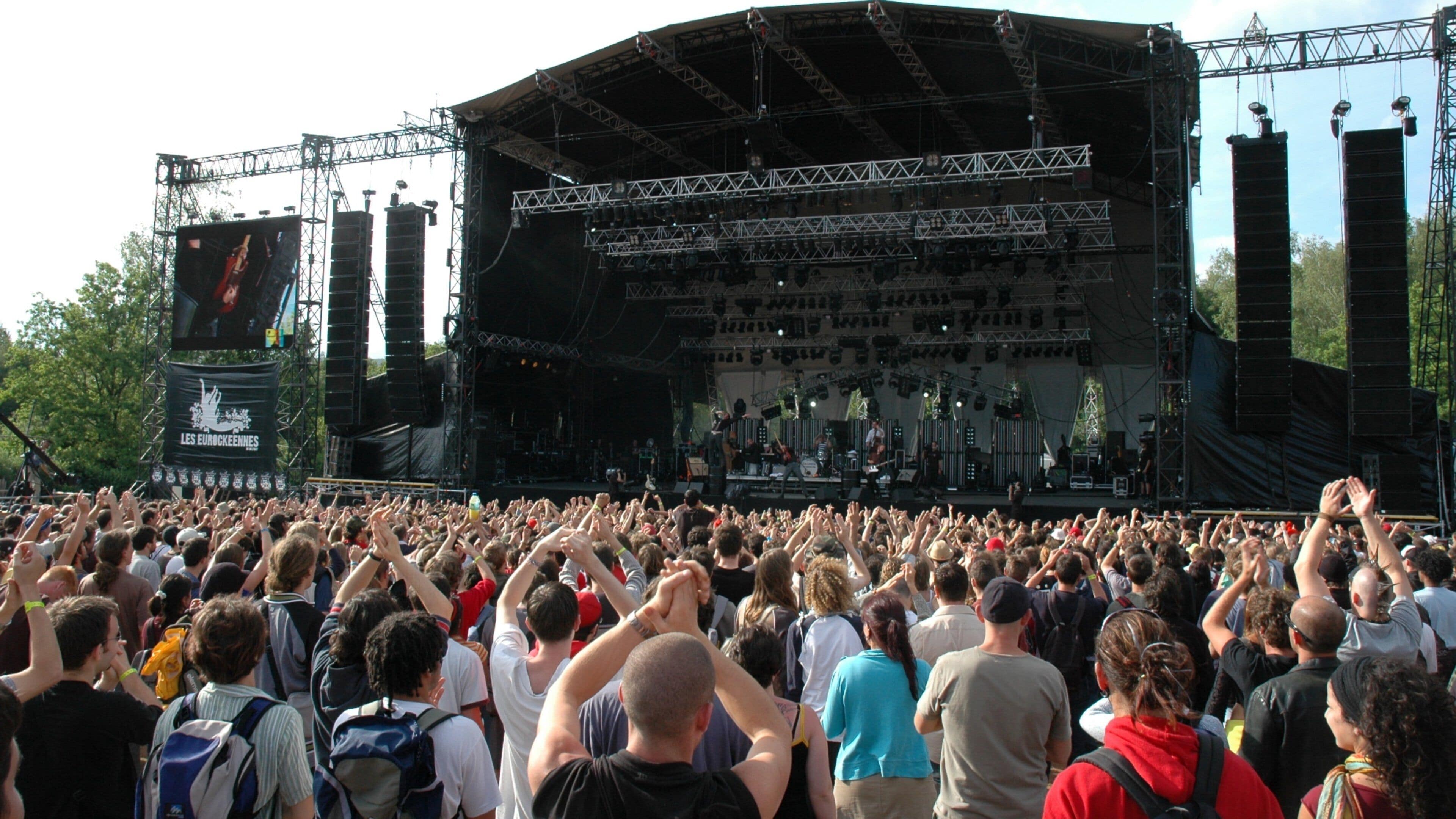 A large outdoor concert with a stage and a crowd of people.