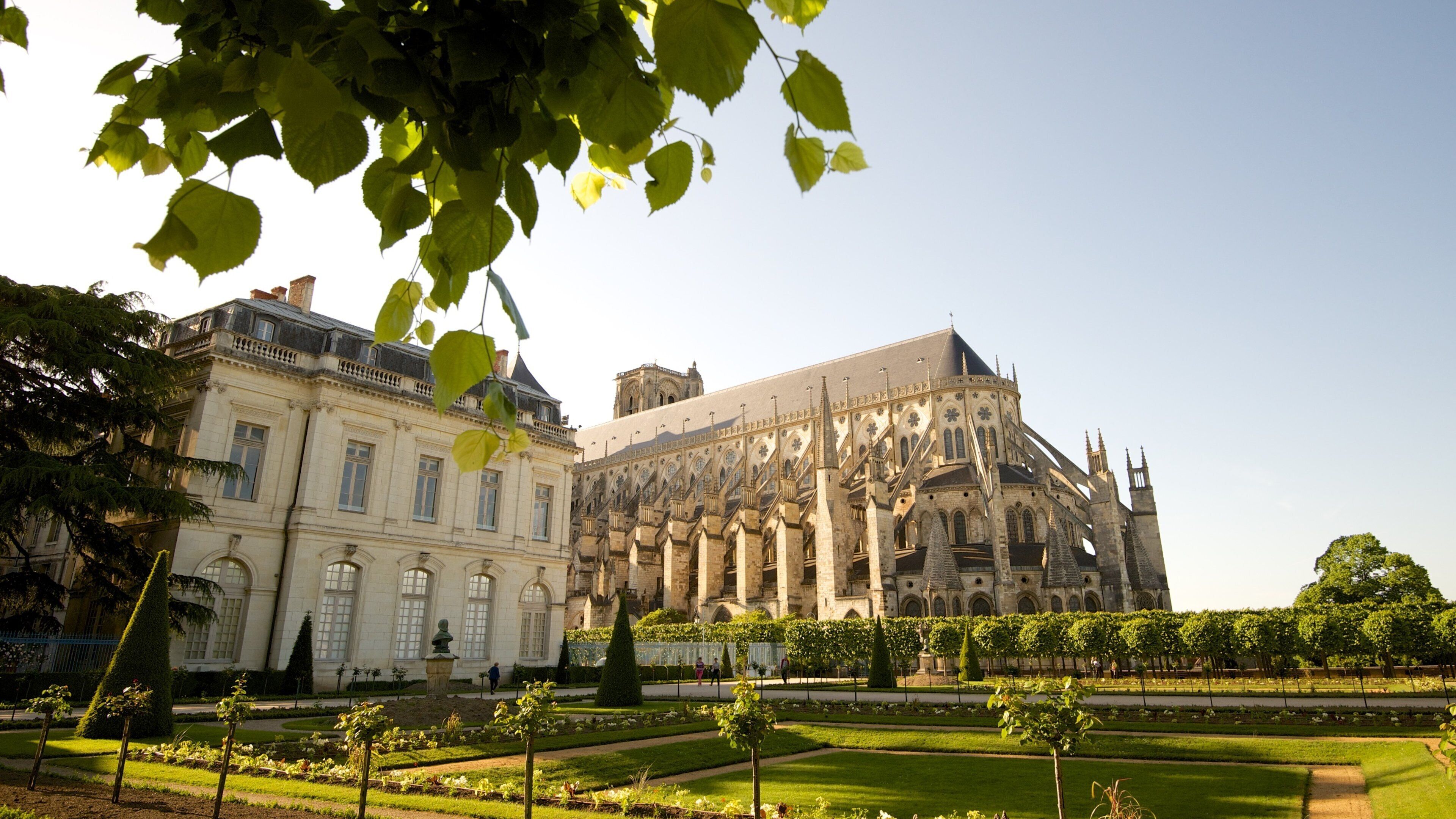 A historic building with intricate architecture and a well-maintained garden.