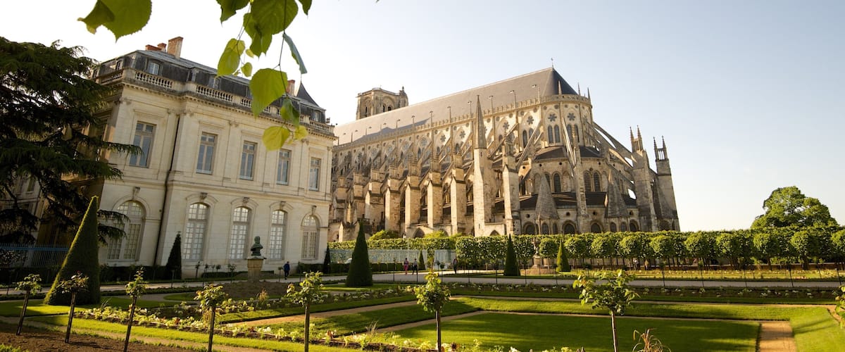A historic building with intricate architecture and a well-maintained garden.