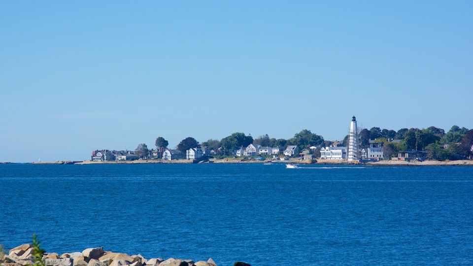 A coastal town with a prominent lighthouse, houses, and a rocky shoreline.