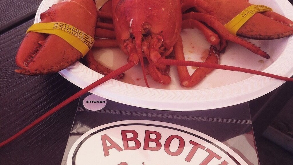A lobster on a plate with a sign for Abbott's in Noank, CT.