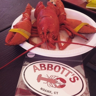 A lobster on a plate with a sign for Abbott's in Noank, CT.