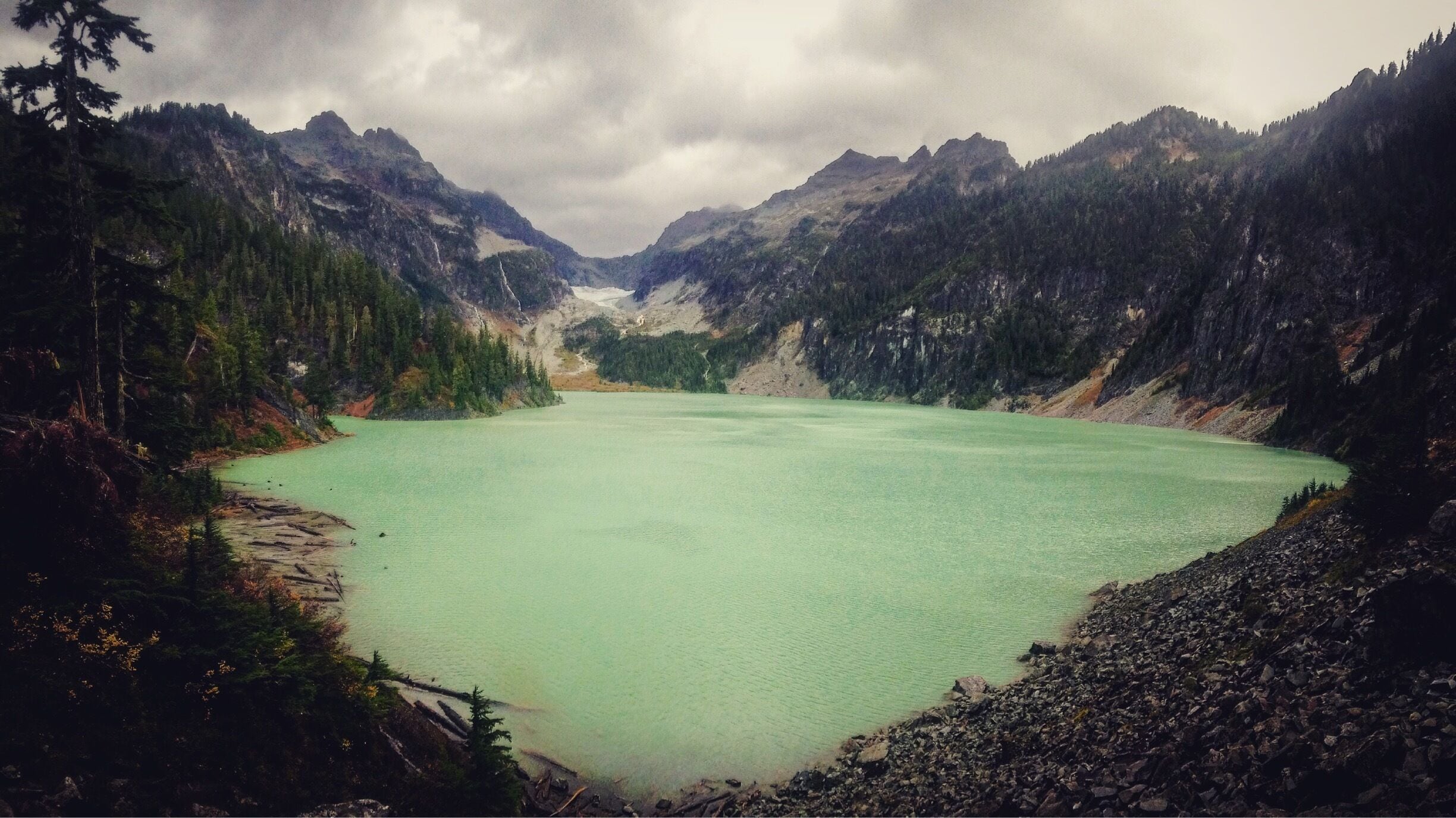 Un lago turquesa rodeado de montañas boscosas.