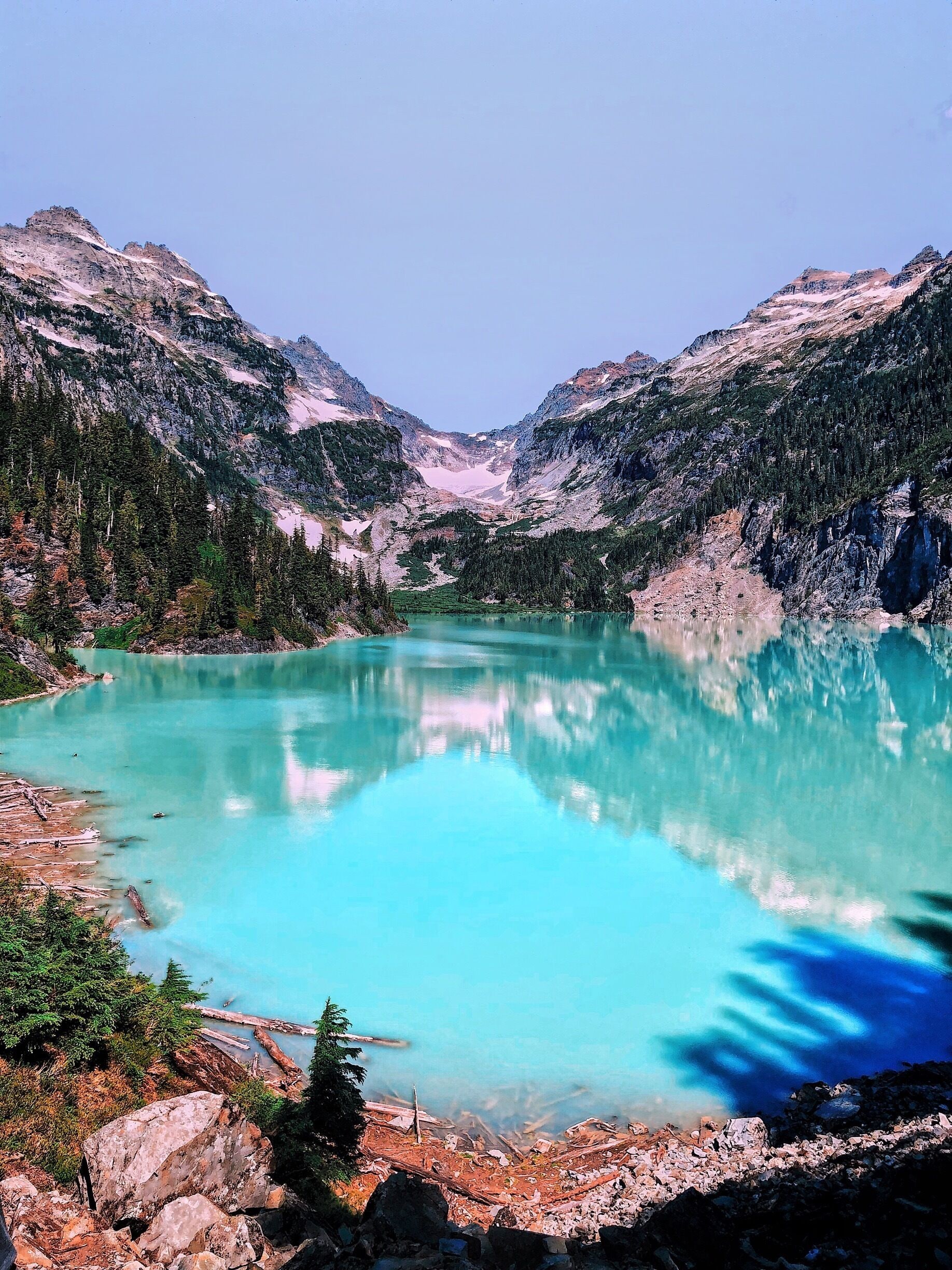 Un lago turquesa rodeado de montañas escarpadas y densos bosques.