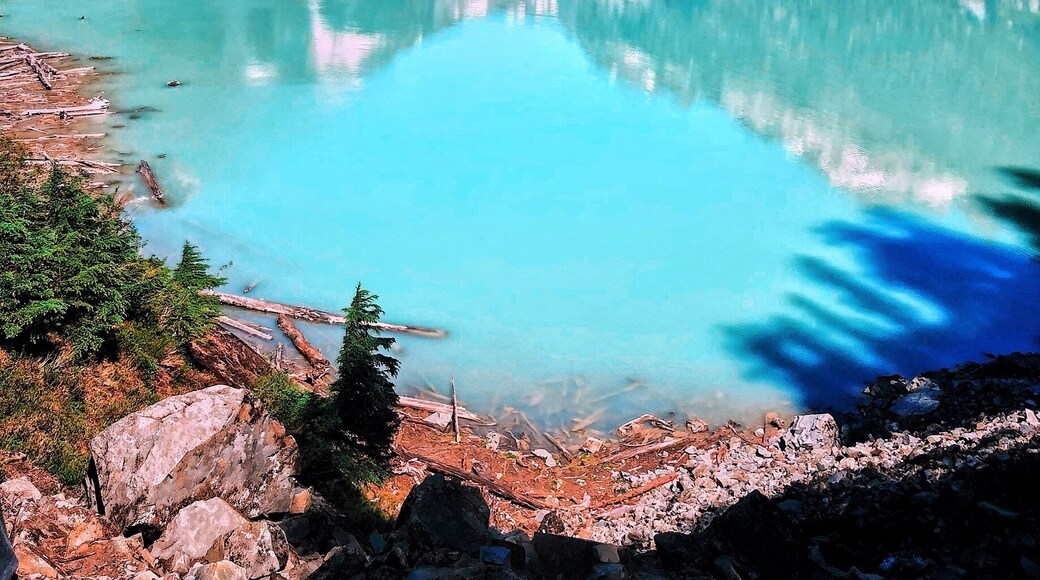 Un lago turquesa rodeado de montañas escarpadas y densos bosques.