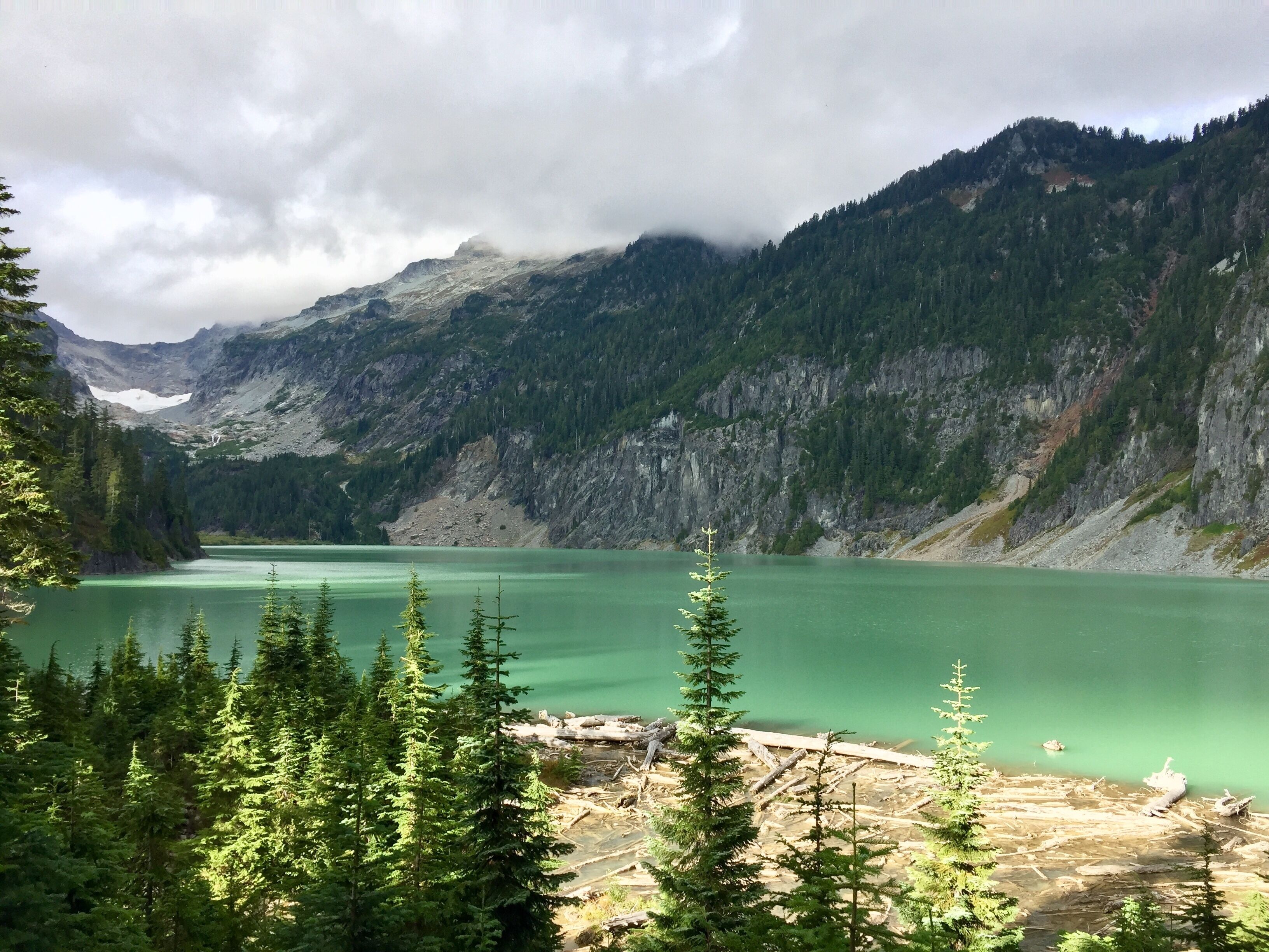 Un lago montano circondato da fitta vegetazione e un terreno aspro.