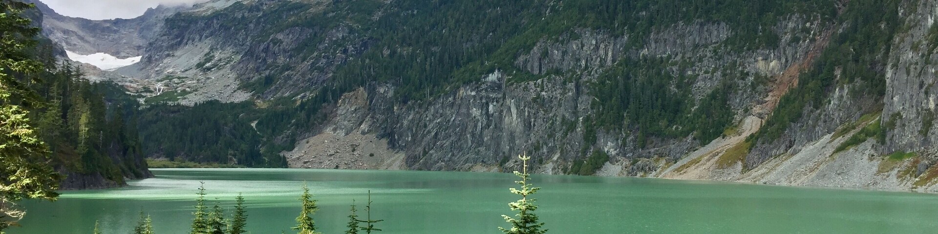Un lago de montaña rodeado de bosque denso y terreno accidentado.