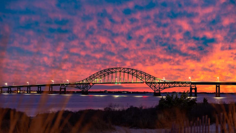 A bridge at sunset with a pink and orange sky.