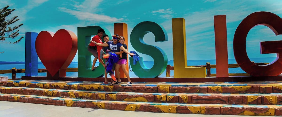 A large sign with the letters 'I', 'V', 'E', 'S', 'L', 'I', 'G' and a heart symbol, with people standing on a set of stairs.