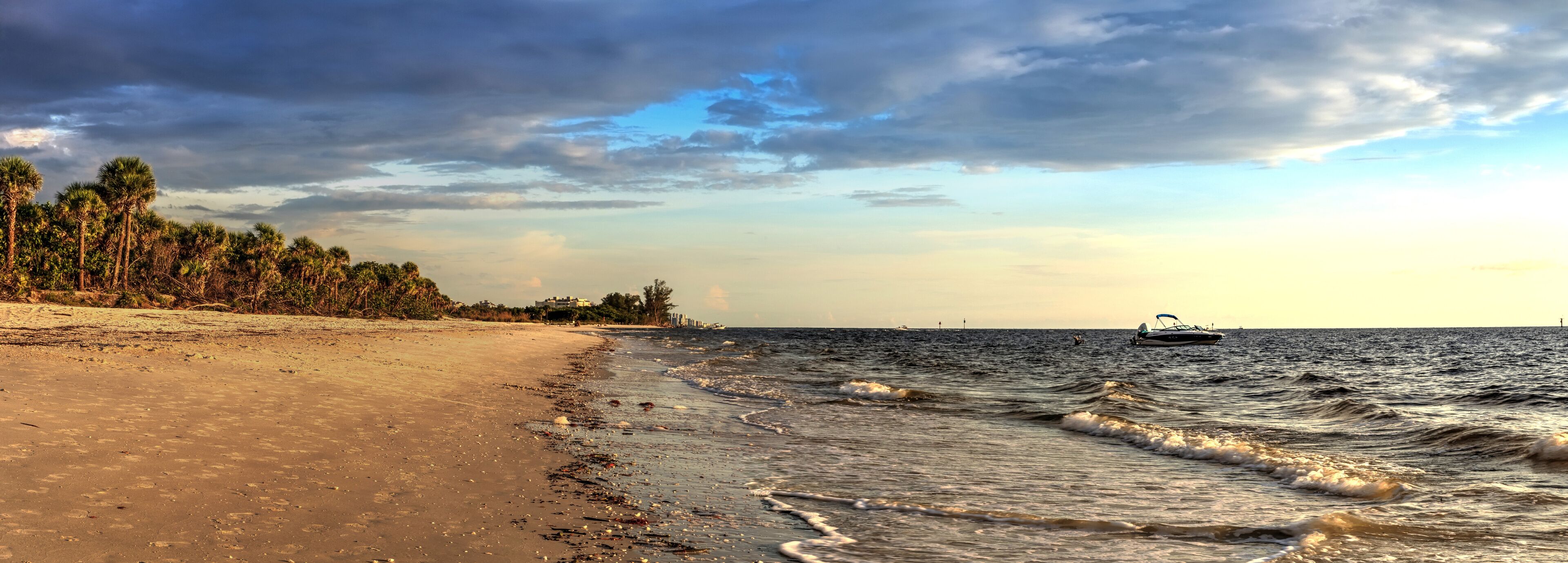 Boat on the waters off Barefoot Beach under dark skies in Bonita Springs