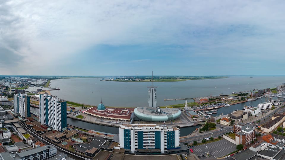 A panoramic view of a city with a river, a prominent tower, and a round building with a dome.