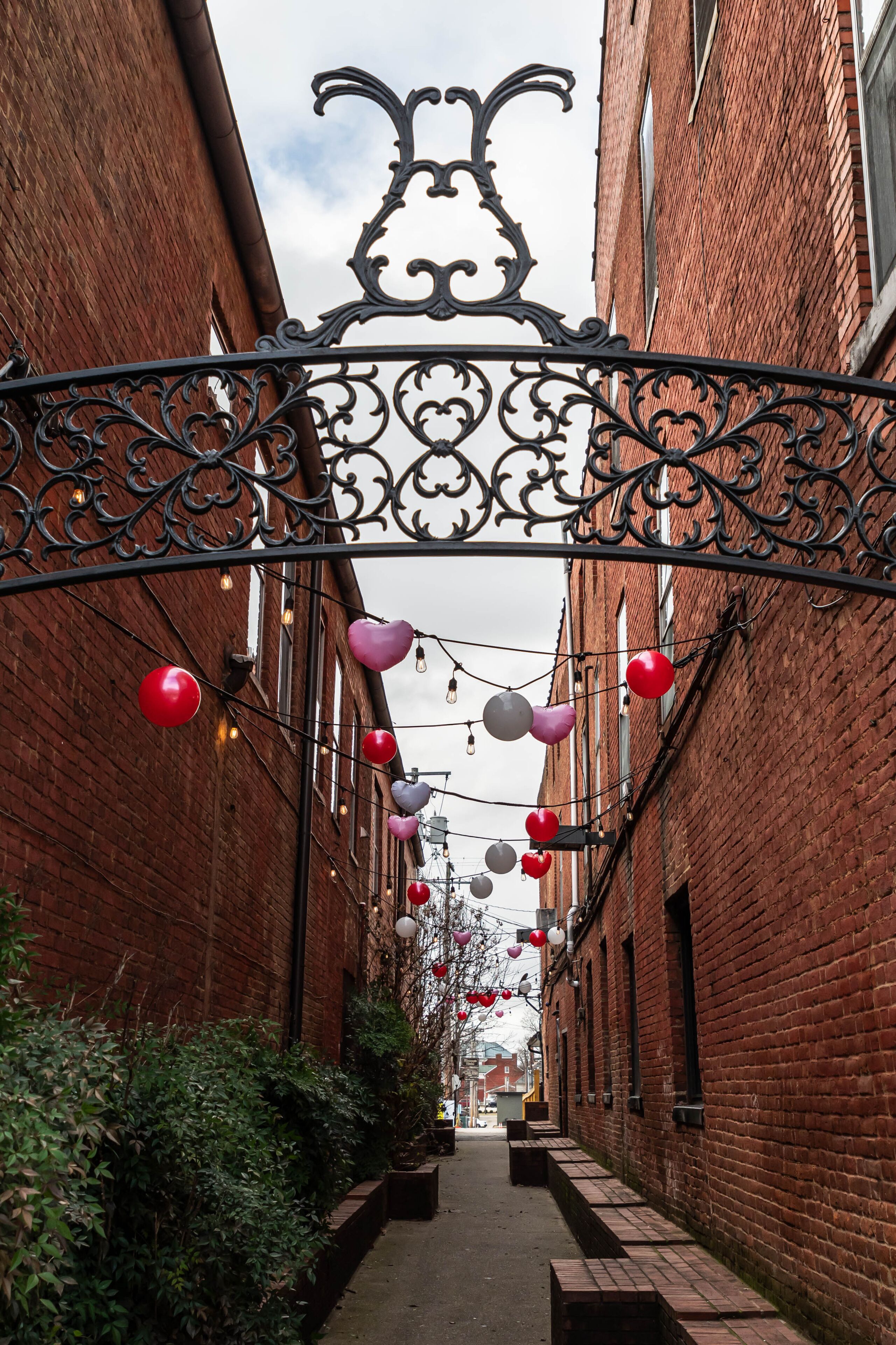 A walkway between two brick buildings decorated for Valentine's Day with benches in Bardstown, Kentucky, USA on an overcast winter day
