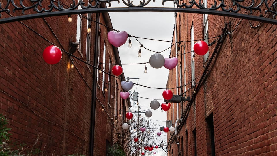 A walkway between two brick buildings decorated for Valentine's Day with benches in Bardstown, Kentucky, USA on an overcast winter day