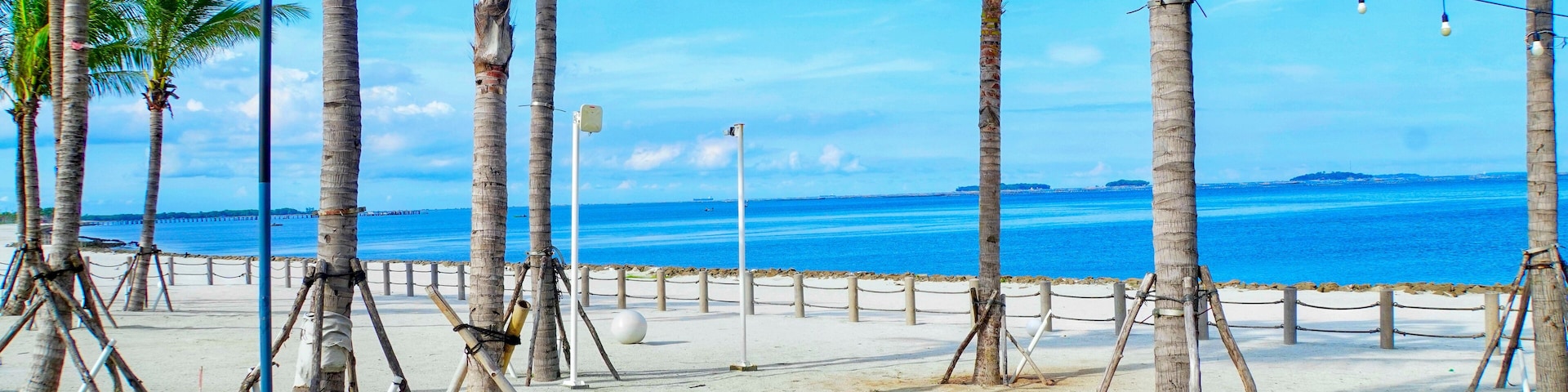 Beautiful landscape of the white sand beach or pantai pasir putih at PIK 2 in Jakarta, Indonesia. Coconut trees, white sand, blue sea, and blue sky