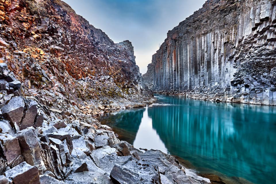 A canyon with a turquoise river, rocky cliffs, and a clear sky.