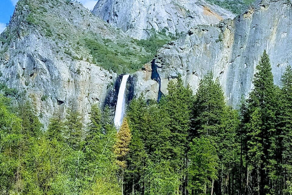 A waterfall cascading down a steep cliff surrounded by dense forest.