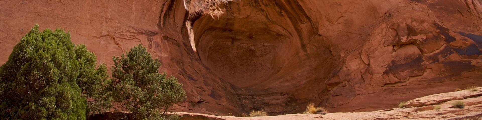 A large red rock arch with a clear blue sky above.