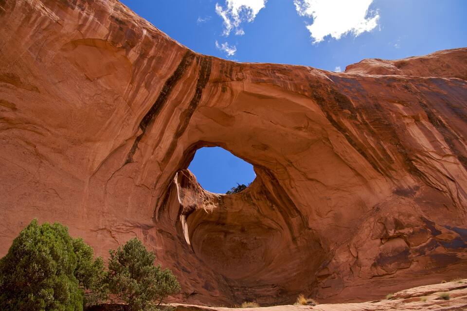 Un gran arco rocoso rojo con un cielo azul claro arriba.