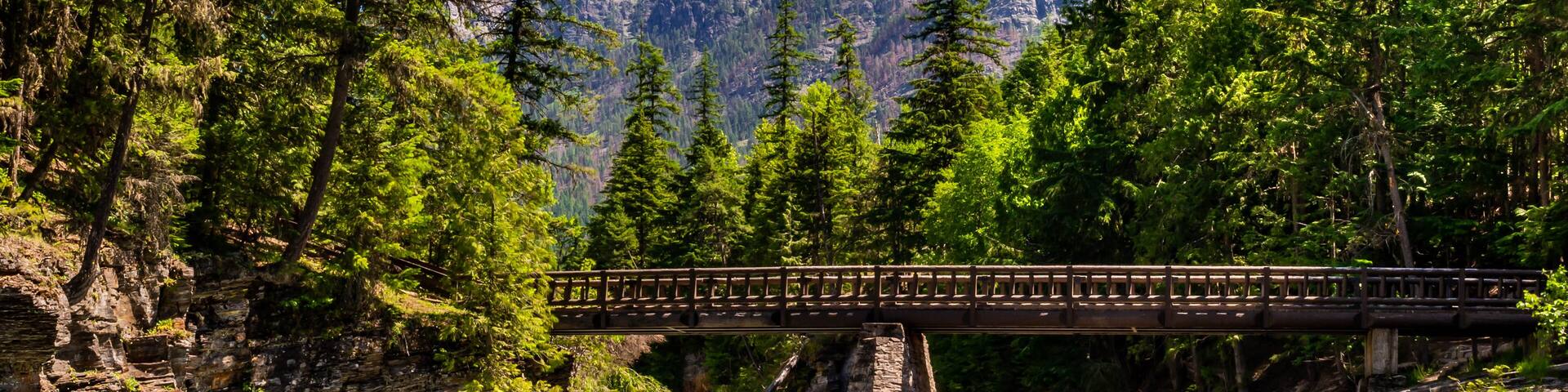 A bridge over a river with a mountainous backdrop.
