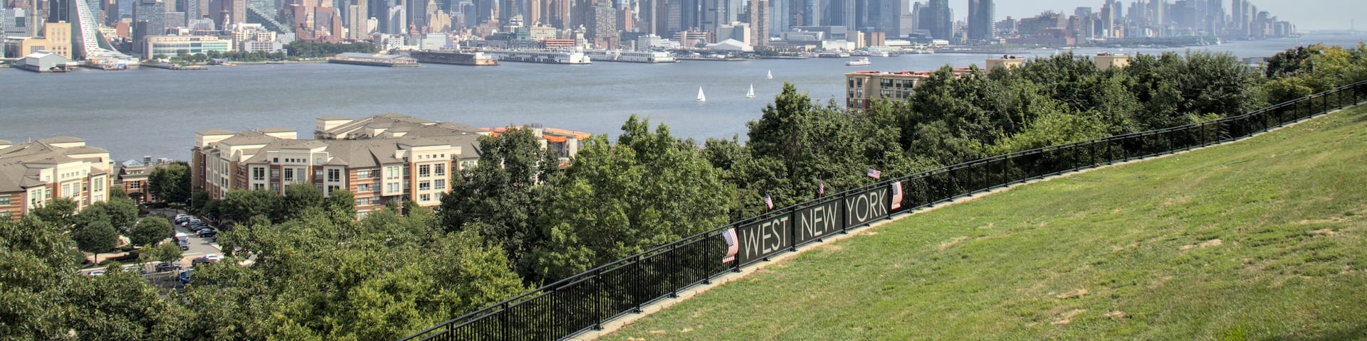 view of midtown manhattan skyline from a public park in west new york (city in jersey, nj, nyc) green space urban living hudson river blue sky clouds skyscraper cityscape high rise