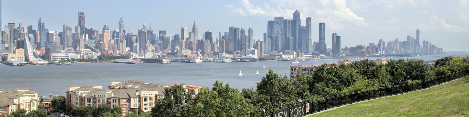 view of midtown manhattan skyline from a public park in west new york (city in jersey, nj, nyc) green space urban living hudson river blue sky clouds skyscraper cityscape high rise