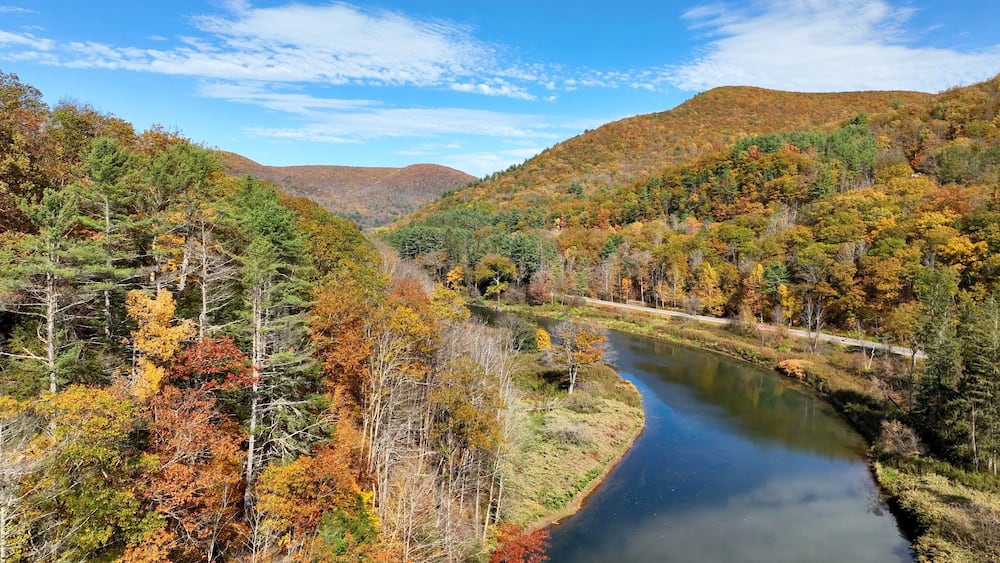 A river winding through a forested valley with autumn foliage.