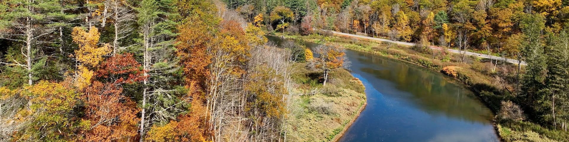 A river winding through a forested valley with autumn foliage.