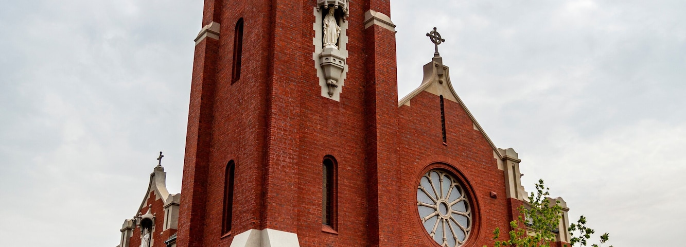 Una iglesia de ladrillo rojo con una torre de reloj y una cúpula.