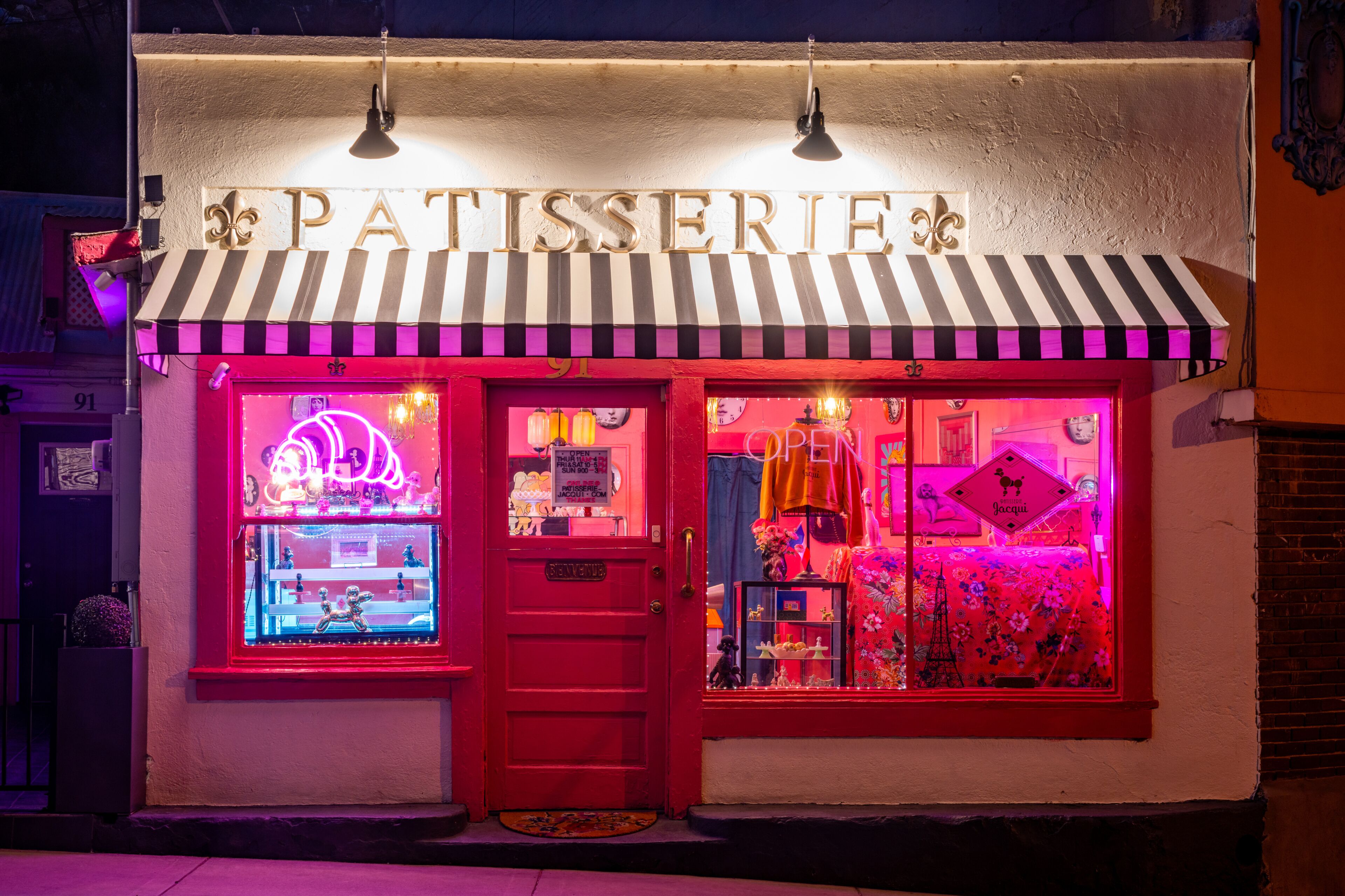 A storefront with a striped awning and neon signage.