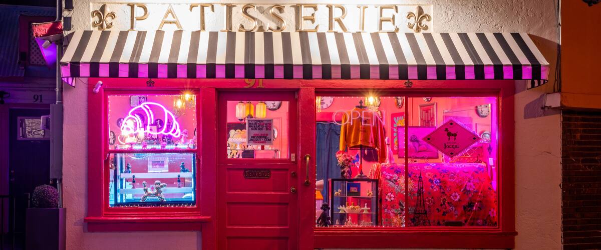 A storefront with a striped awning and neon signage.
