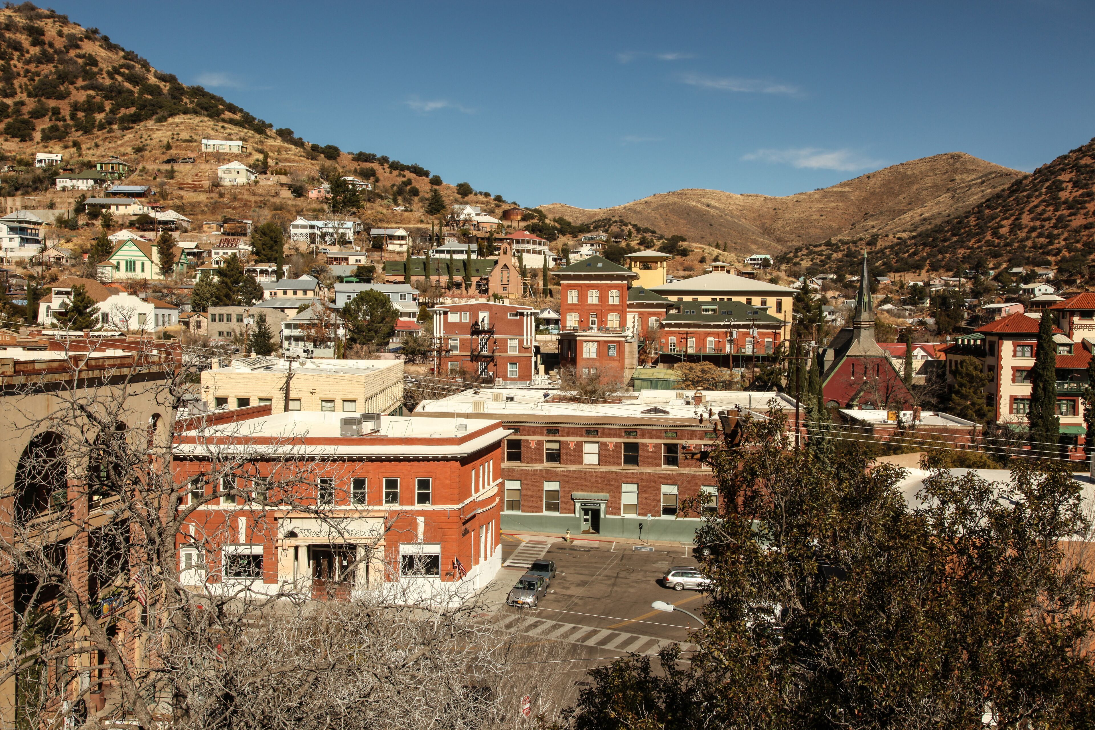 A town with historic buildings, a church, and a hilly backdrop.