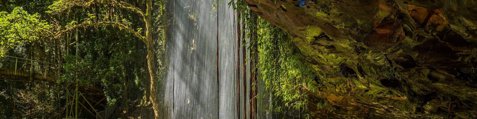 A waterfall in a forested area with a person standing nearby.