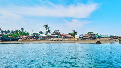 A coastal village with boats, houses, and palm trees.